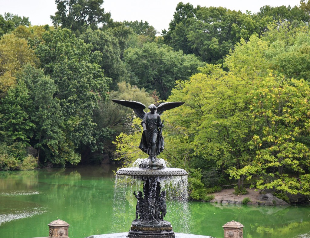 Bethesda Fountain Angel with lake and trees in the background.